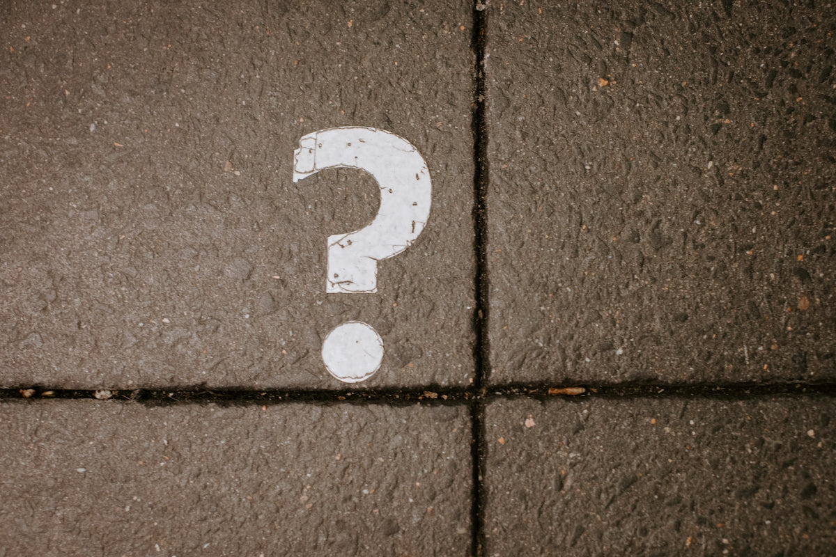 White question mark painted on concrete pavement