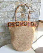 Flora - Borsa in rafia intrecciata fatta a mano con fiore in ambra all'uncinetto